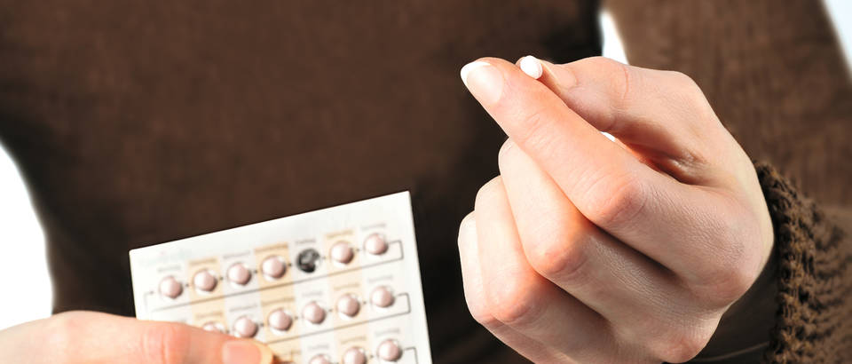 Woman holding contraceptive pill